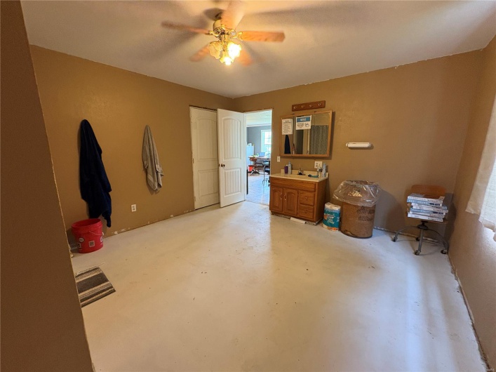 Bedroom with concrete floors, a closet, a ceiling fan, and a sink