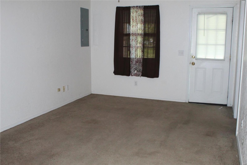 Carpeted spare room featuring electric panel and baseboards