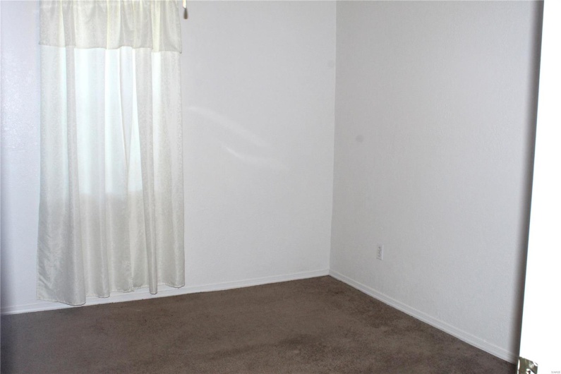 Spare room with baseboards and dark carpet