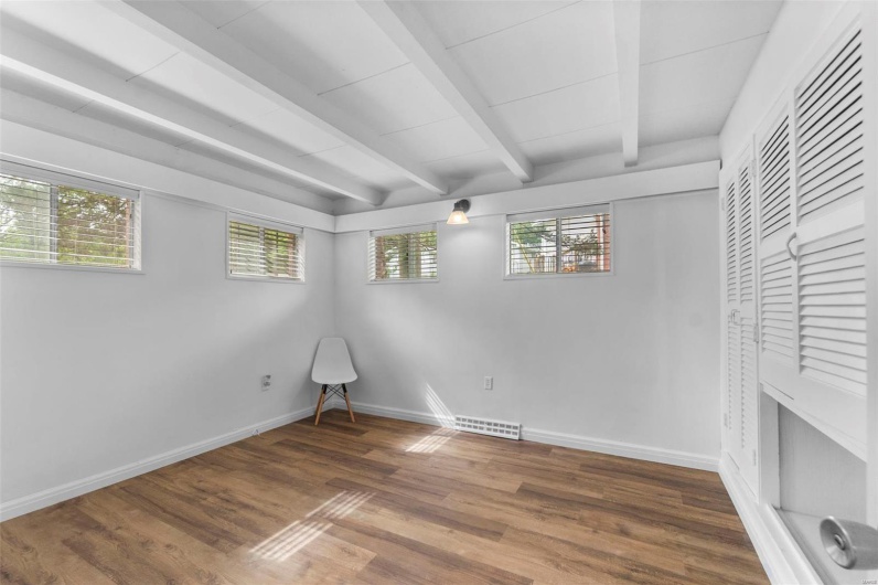Spare room featuring beamed ceiling, wood finished floors, and baseboards