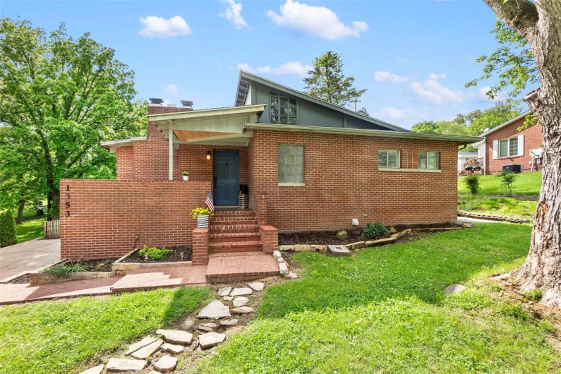 Rear view of property with entry steps, a lawn, brick siding, and a chimney