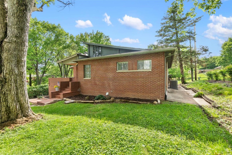 Back of house featuring central AC, a lawn, a patio area, and brick siding
