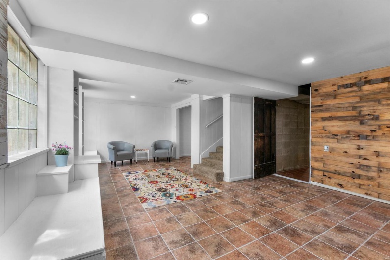 Basement with stairs, recessed lighting, wooden walls, and dark tile patterned flooring