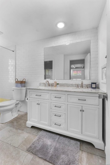 Bathroom featuring toilet, double vanity, and stone finish floors