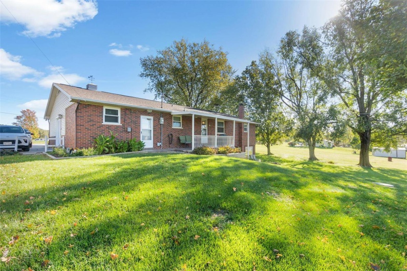 Ranch-style home featuring a garage, a front lawn, and a porch
