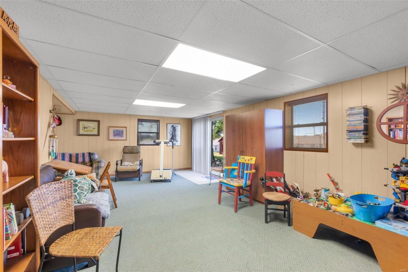 Recreation room with wood walls, carpet flooring, and a drop ceiling