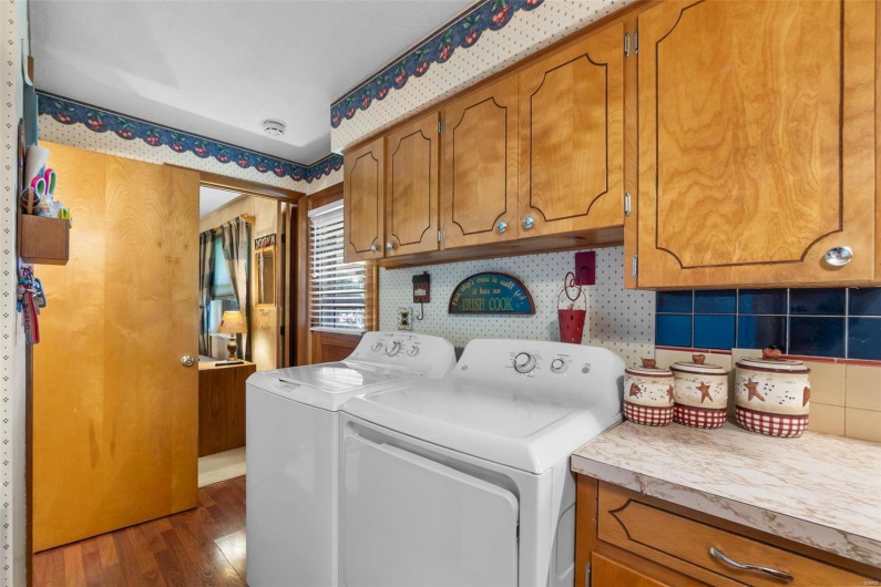 Laundry room featuring dark hardwood / wood-style flooring, washing machine and dryer, and cabinets