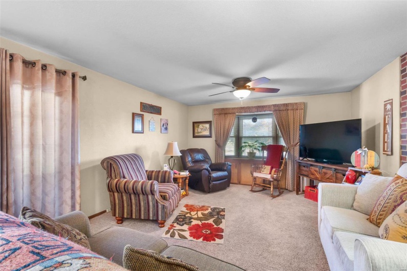 Carpeted living room featuring ceiling fan