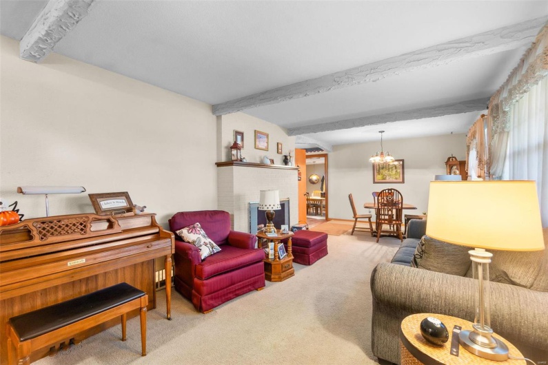 Carpeted living room with beamed ceiling and a notable chandelier