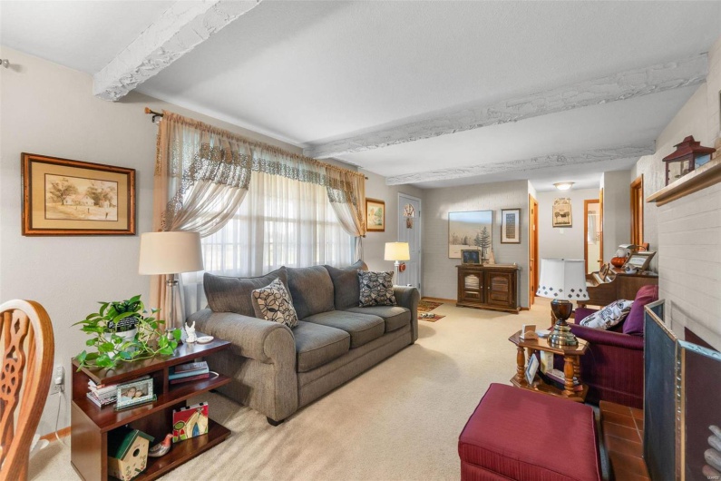 Carpeted living room featuring beamed ceiling