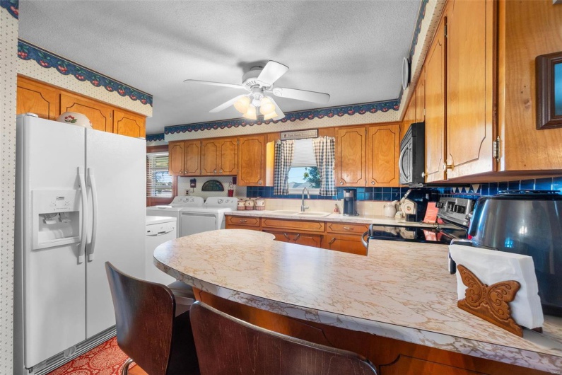 Kitchen with kitchen peninsula, ceiling fan, independent washer and dryer, sink, and stainless steel appliances