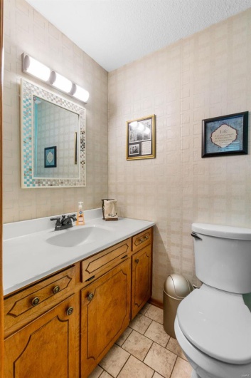 Bathroom with toilet, a textured ceiling, vanity, and tile patterned flooring