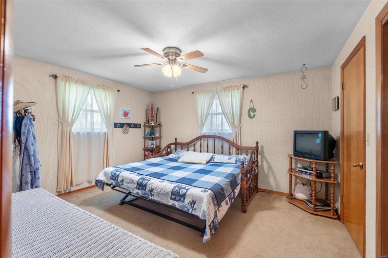 Carpeted bedroom with multiple windows, a textured ceiling, and ceiling fan