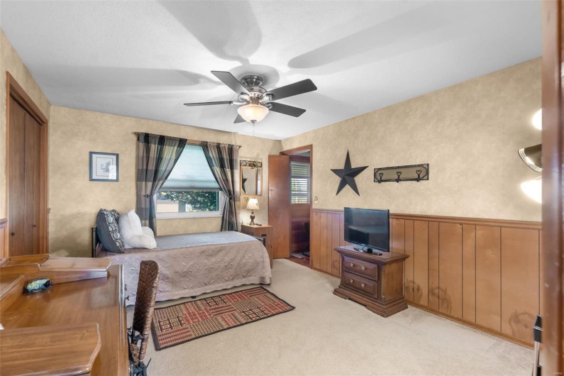 Carpeted bedroom with wood walls, a textured ceiling, a closet, and ceiling fan