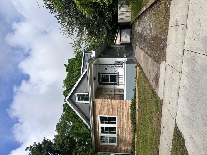 Bungalow-style house featuring a porch, driveway, stone siding, and an outbuilding