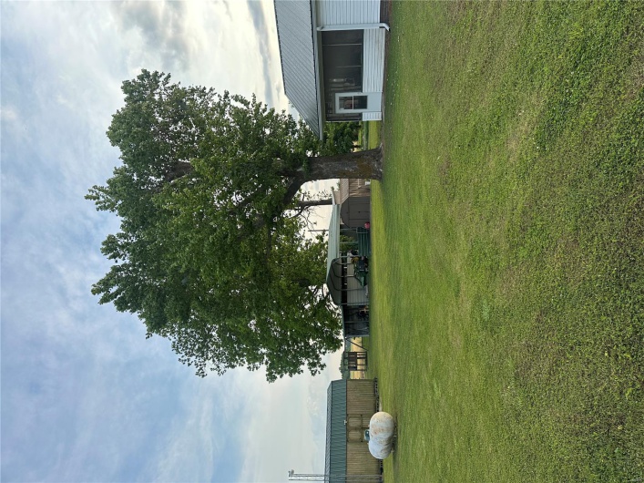View of green lawn with a detached carport, an outdoor structure, and a storage unit