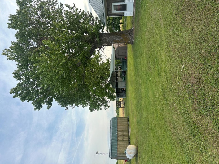 View of green lawn featuring a detached carport, an outdoor structure, and a shed