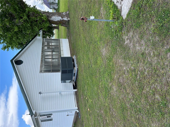 Back of house with cooling unit, a lawn, and a sunroom