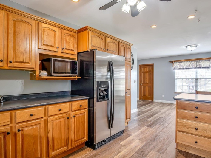Kitchen featuring appliances with stainless steel finishes, dark countertops, ceiling fan, brown cabinetry, and recessed lighting
