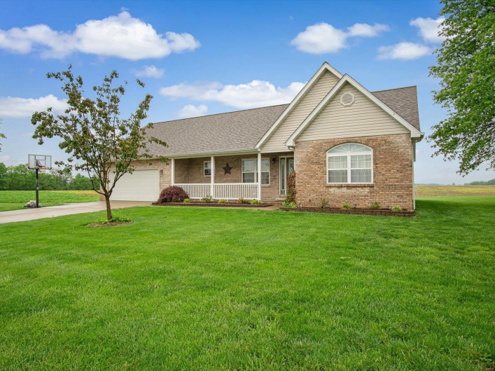 Ranch-style house featuring a porch, driveway, a garage, brick siding, and a front lawn