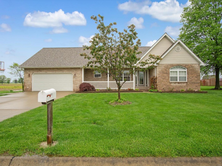 Single story home with a garage, a front yard, brick siding, a shingled roof, and concrete driveway