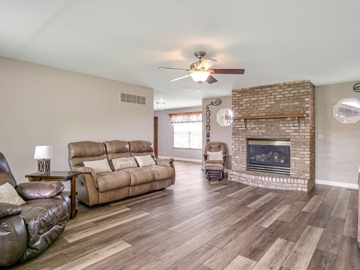 Living area featuring wood finished floors, ceiling fan, a fireplace, and baseboards