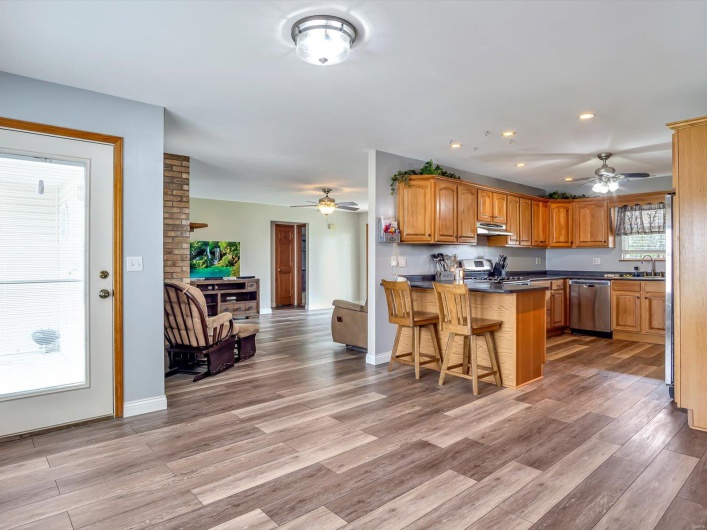 Kitchen featuring dishwasher, ceiling fan, a peninsula, under cabinet range hood, and light wood finished floors