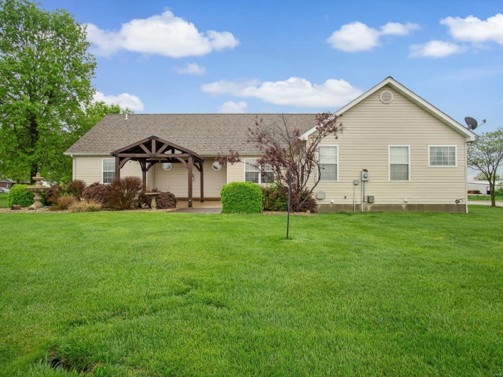 Rear view of property featuring a gazebo, a shingled roof, and a lawn