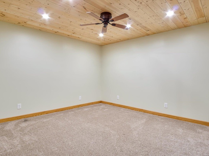 Carpeted empty room with a ceiling fan, baseboards, and wooden ceiling