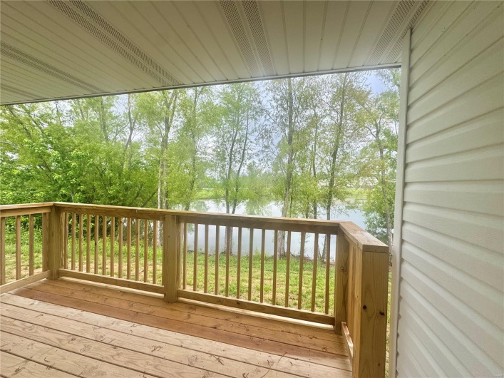 Wooden terrace featuring a water view and view of wooded area