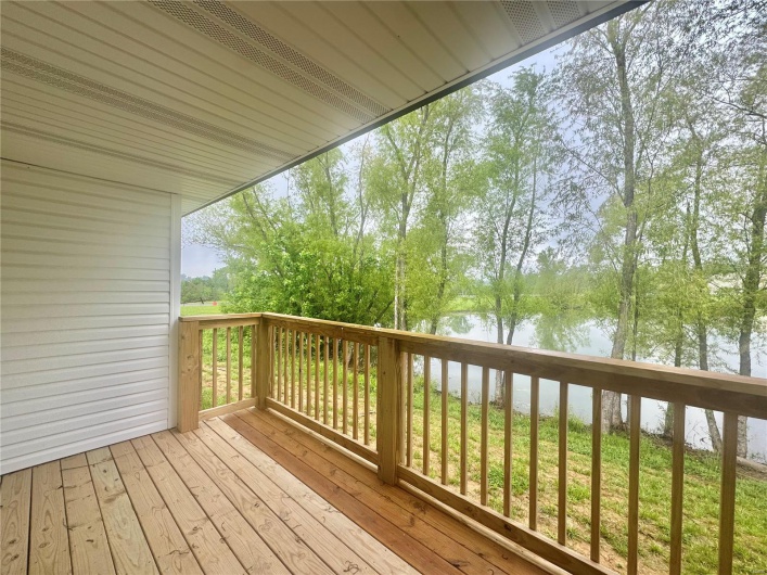 Wooden terrace featuring a water view and view of wooded area