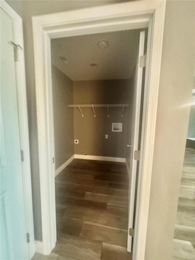Clothes washing area with wood finished floors, hookup for a washing machine, and baseboards