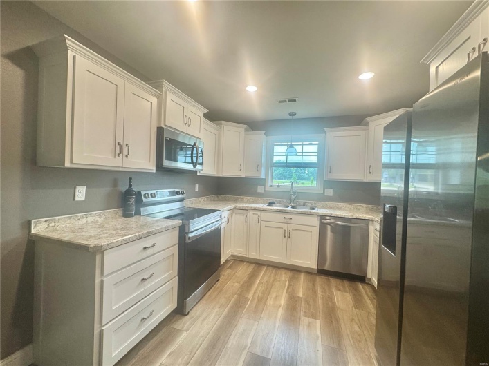 Kitchen featuring appliances with stainless steel finishes, a sink, light wood-style floors, white cabinetry, and recessed lighting
