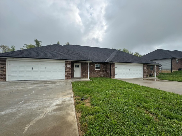 Ranch-style home with concrete driveway, an attached garage, and brick siding