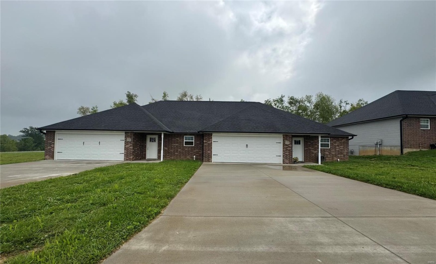 Ranch-style home featuring a front lawn, driveway, a garage, and brick siding
