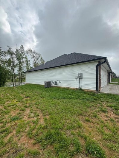 View of property exterior with central AC, a lawn, and an attached garage
