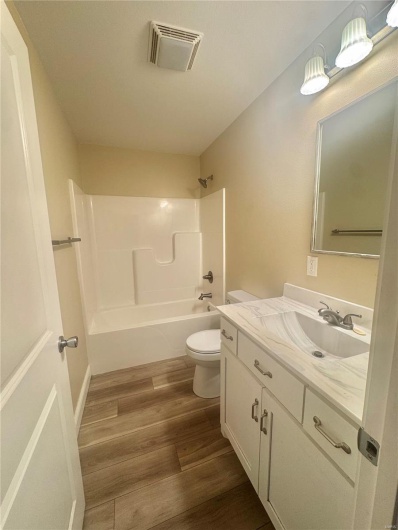 Full bathroom with toilet, bathing tub / shower combination, vanity, and wood finished floors