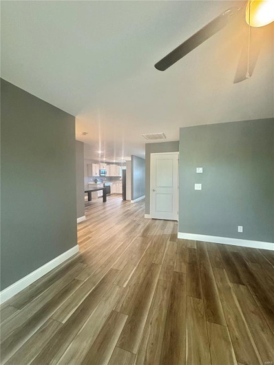 Unfurnished living room with wood finished floors, baseboards, and a ceiling fan