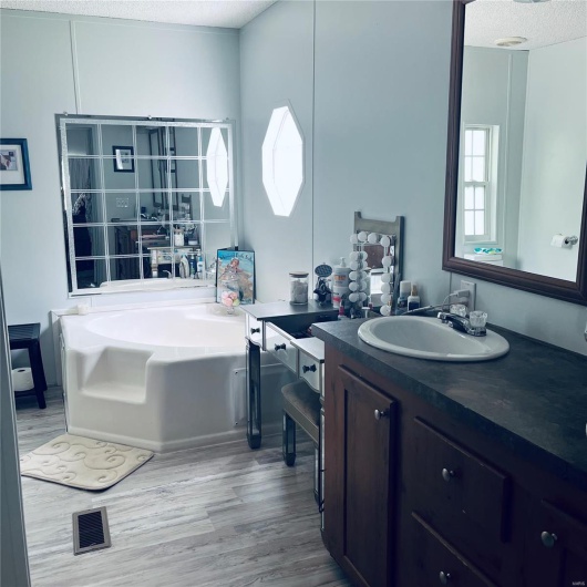 Full bath featuring wood finished floors, a bath, vanity, and a textured ceiling