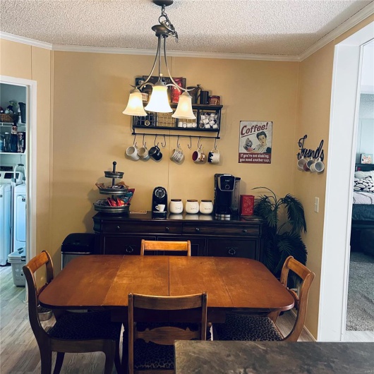 Dining room with washer and dryer, ornamental molding, wood finished floors, and a textured ceiling