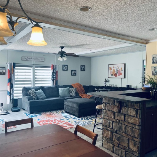 Living area with a textured ceiling, ceiling fan, and ornamental molding