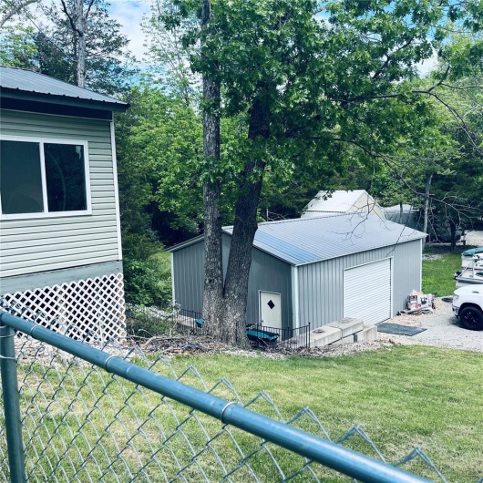 View of side of home with metal roof, an outdoor structure, and a detached garage