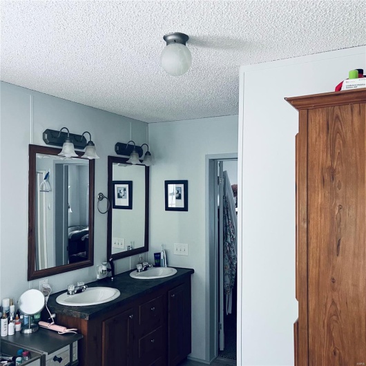 Bathroom with a textured ceiling and double vanity