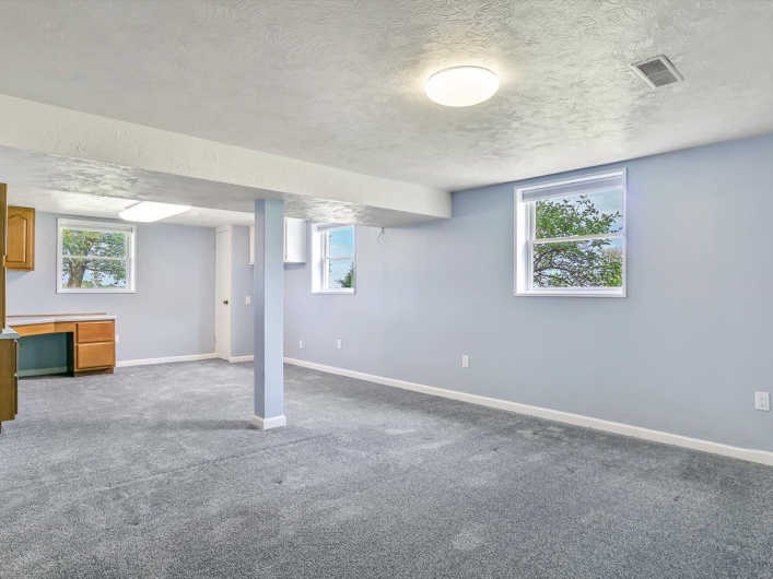 Below grade area featuring a textured ceiling, baseboards, carpet flooring, and healthy amount of natural light