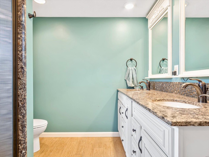 Full bathroom with wood finished floors, tasteful backsplash, double vanity, toilet, and baseboards