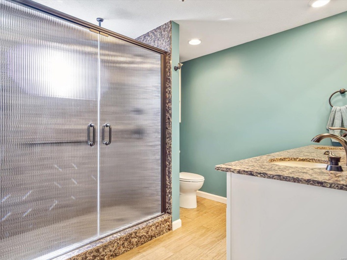 Full bathroom featuring wood finished floors, toilet, a shower stall, vanity, and recessed lighting