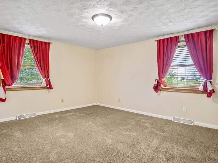 Carpeted spare room with plenty of natural light, a textured ceiling, and baseboards