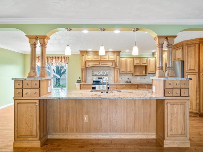 Kitchen with a sink, a kitchen island with sink, light wood-type flooring, backsplash, and crown molding