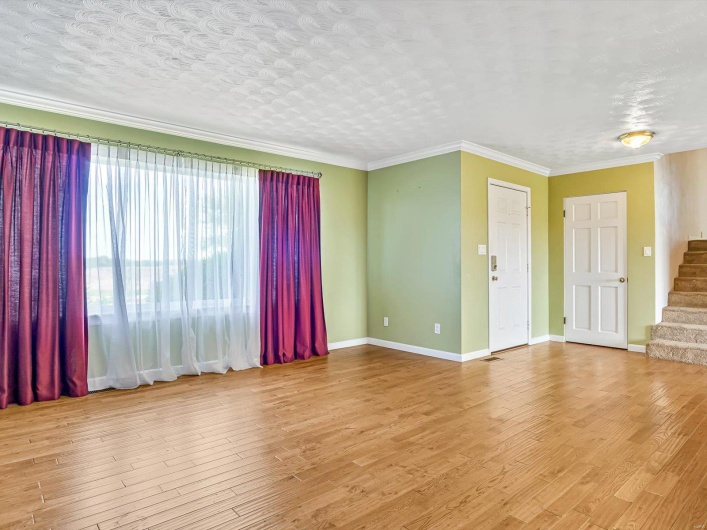 Unfurnished room with stairs, wood finished floors, baseboards, and crown molding