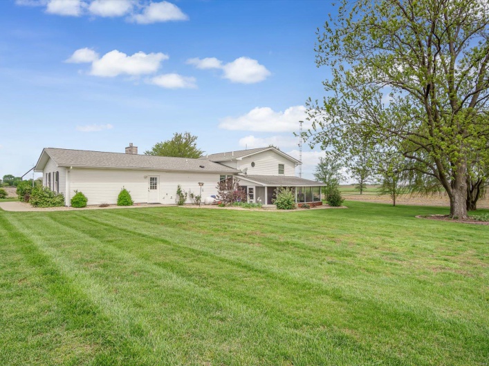 Rear view of house with a lawn, a sunroom, and a chimney